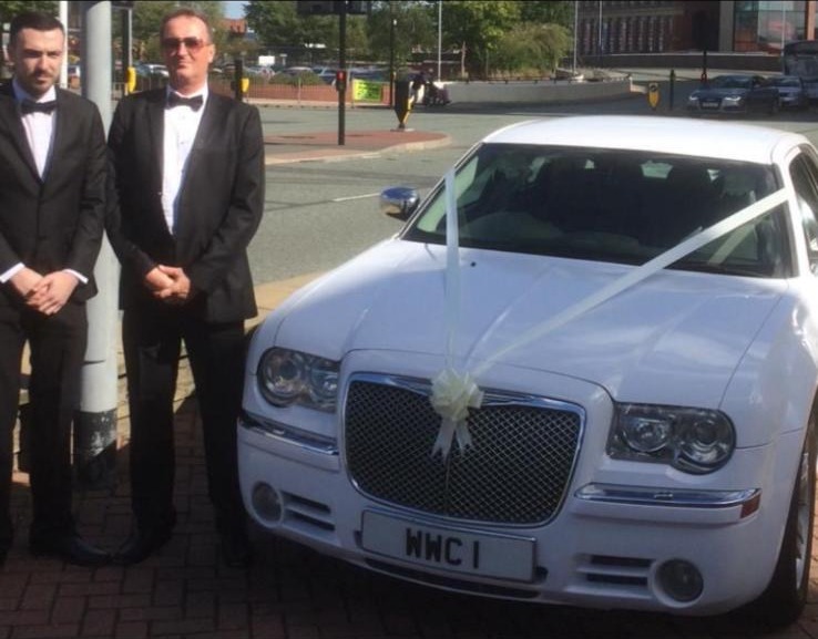Two gentlemen beside the white Baby Bentley
